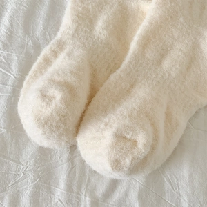 Nahaufnahme der dicken cremeweißen warmen Plüschsocken aus weichem Korallenvlies