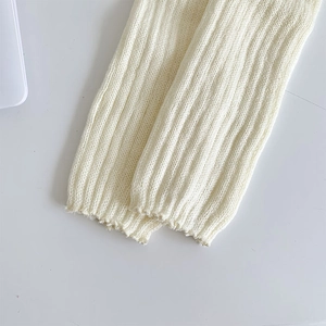 Gros plan sur des jambières en maille côtelée blanc crème au tissu doux et élastique