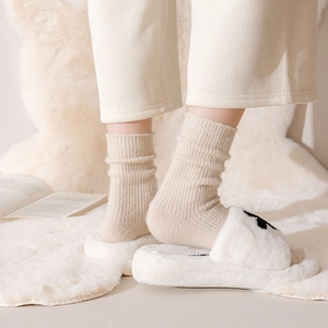 Close-up of cream ribbed thermal cotton socks with vertical knit texture and plush slippers