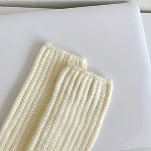 Détail macro de la texture en maille côtelée crème et de la bordure élastique des jambières