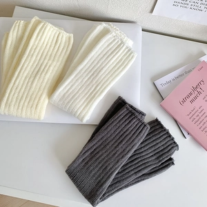 Détails de la maille côtelée des jambières en couleurs crème, blanc et gris foncé