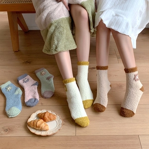 Close-up of warm coral fleece socks with colorful patchwork and cute embroidery details