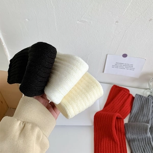 Détail de jambières en maille côtelée épaisse en noir, blanc, beige, rouge et gris