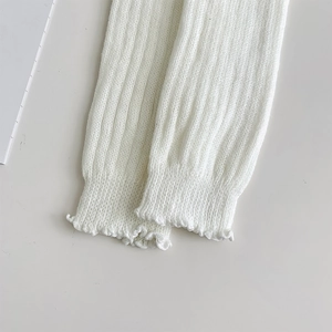 Detail von weißen Strick-Stulpen mit vertikalem Rippmuster und gerüschten Wellensäumen