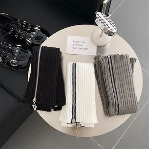 Close-up of knit leg warmers with vertical ribs and metal zippers in black white and grey