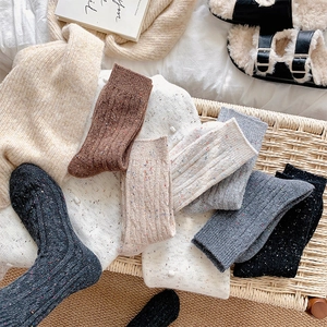 Thick wool blend cable knit crew socks with colorful flecks in a cozy home setting