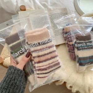 Gros plan de chaussettes douces à rayures en sachets cadeaux sur un lit douillet