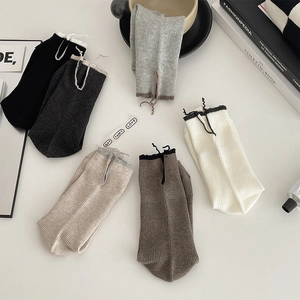 Detail of ribbed knit crew socks with lettuce edge trim and drawstring in six earthy tones