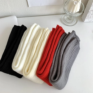 Gros plan de jambières en tricot épais à côtes en noir, crème, rouge et gris foncé