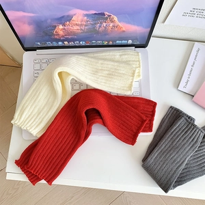 Détail de jambières en maille montrant la texture côtelée en blanc, rouge et gris
