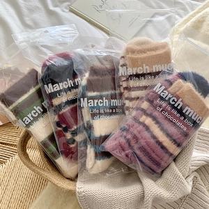 Détail de cinq chaussettes pelucheuses à rayures en sachets individuels dans un décor cosy