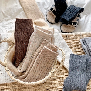 Close-up of thick knitted crew socks in varied colors with tweed pattern and ribbing