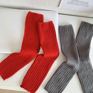 Détail de jambières en maille torsadée rouge et grise avec texture côtelée pour l'hiver