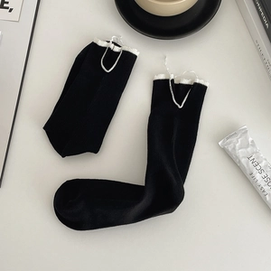 Detailed view of black cotton socks with white lettuce trim and ribbed texture
