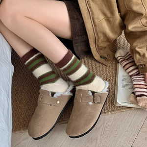 Gros plan de chaussettes rayées douillettes avec mules fourrées sur un tapis chaleureux