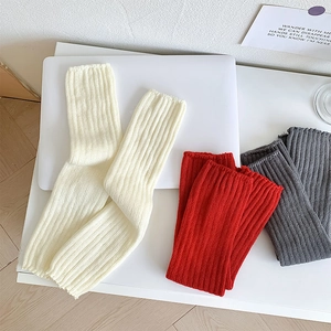 Vue détaillée de jambières en tricot crème, rouge et gris avec motifs à rayures verticales