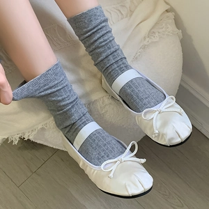 Detail of white ballet flats with elastic strap and grey ribbed cotton socks