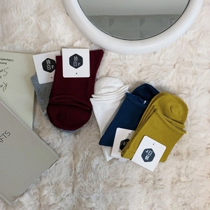 Multipack of minimalist cotton crew socks in assorted colors on soft white carpet