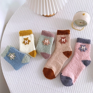 Detailed view of thick coral fleece socks with cute bear patch in five warm colors