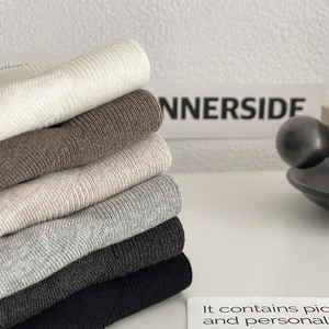 Close-up of six vertical ribbed knit socks in assorted neutral colors stacked neatly
