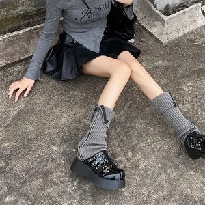 Detail of grey knitted leg warmers with metal zipper decoration on outdoor street background