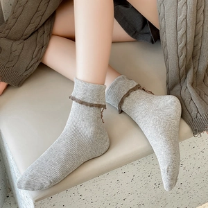 Grey knit crew socks with vintage brown ruffle cuffs and vertical ribbed texture pattern