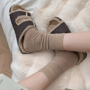Detail of dark brown faux leather sandals with fur lining and silver metal buckles