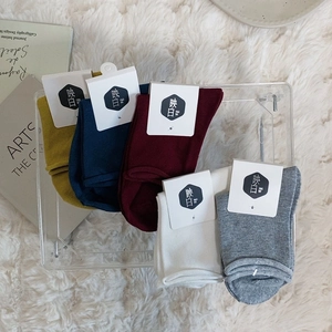 Close-up of colorful cotton crew socks in yellow, burgundy and blue on white plush