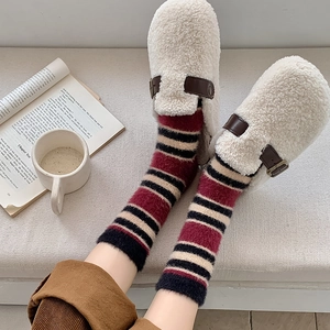 Gros plan de chaussettes épaisses à rayures en fausse fourrure et de mules moelleuses