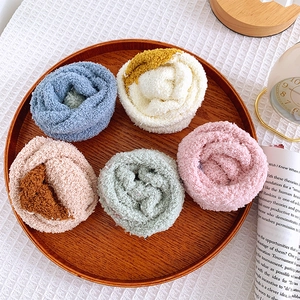 Detail of soft coral fleece socks in five warm colors displayed on a wooden tray