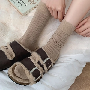 Close-up of khaki ribbed crew socks paired with brown faux fur buckled slippers