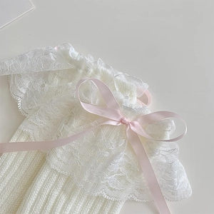 Dettaglio di scaldamuscoli in pizzo bianco con fiocco in raso rosa e maglia a coste