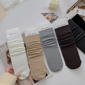 Detail of five pairs of rib-knit slouch socks in neutral colors with packaging