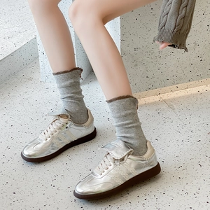 Close-up of metallic silver sneakers with cream stripes and a durable gum sole
