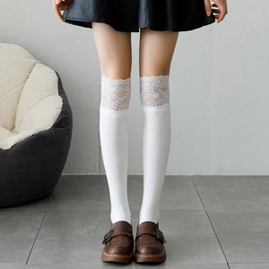 Detail of white over-the-knee socks with delicate lace trim and vertical knit texture