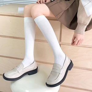 Detail of white Japanese school style high socks with loafers and pleated skirt