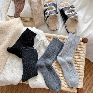Close-up of thick speckled knit socks in various colors on a cozy home setting background