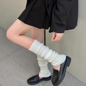 Gros plan de jambières en tricot côtelé blanc avec mocassins noirs à plateforme style JK