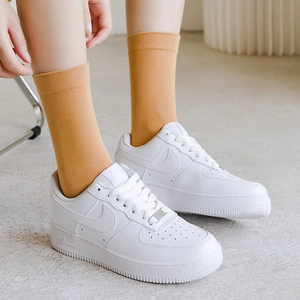 Nahaufnahme von hellorangen Socken kombiniert mit klassischen weißen Sneakern für Freizeit