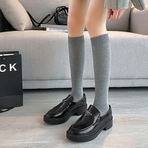 Detailed shot of grey knit knee-high socks paired with black platform leather loafers