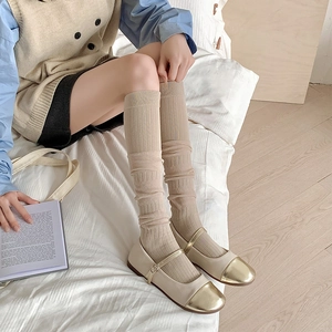 Gros plan sur des chaussettes montantes beiges avec texture rayée et effet plissé