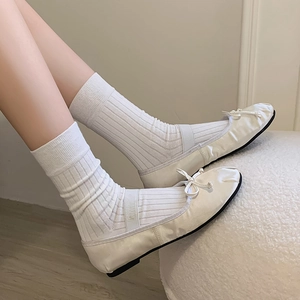 Close-up of white vertical striped calf socks with ballet flats and ribbon bow detail