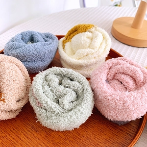 Five pairs of assorted thick coral fleece socks in soft pastel colors displayed on wood