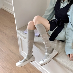 Détail de chaussettes hautes à côtes verticales gris clair avec ballerines argentées