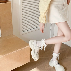 Detail of white lace bow socks paired with white platform Mary Jane leather shoes