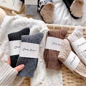 Close-up of thick knitted wool socks with colorful flecks and ribbed cuffs in neutral tones