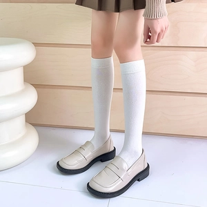 Close-up of white knit knee-high socks paired with cream loafers for a JK school style