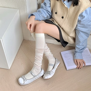 Gros plan sur des chaussettes hautes blanches côtelées avec ballerines en satin argenté