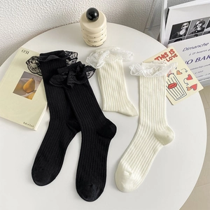 Gros plan de chaussettes en tricot style Lolita avec bordure en dentelle noire et crème