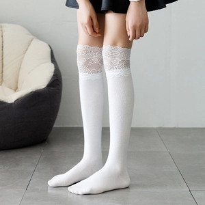 Detailed close-up of white over-knee socks featuring elegant lace trim and knitted texture